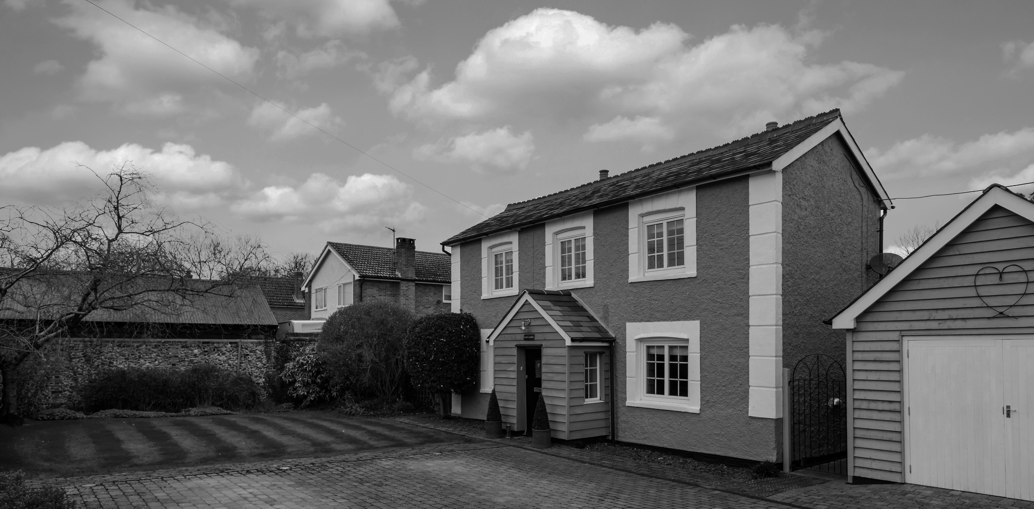 Black and White Photo of a Detached House with a Large Driveway and Seperate Garage